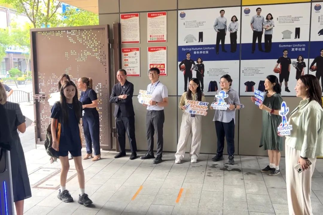 清晨7:30老师在校门口微笑迎接返校学生，开学日温暖问候