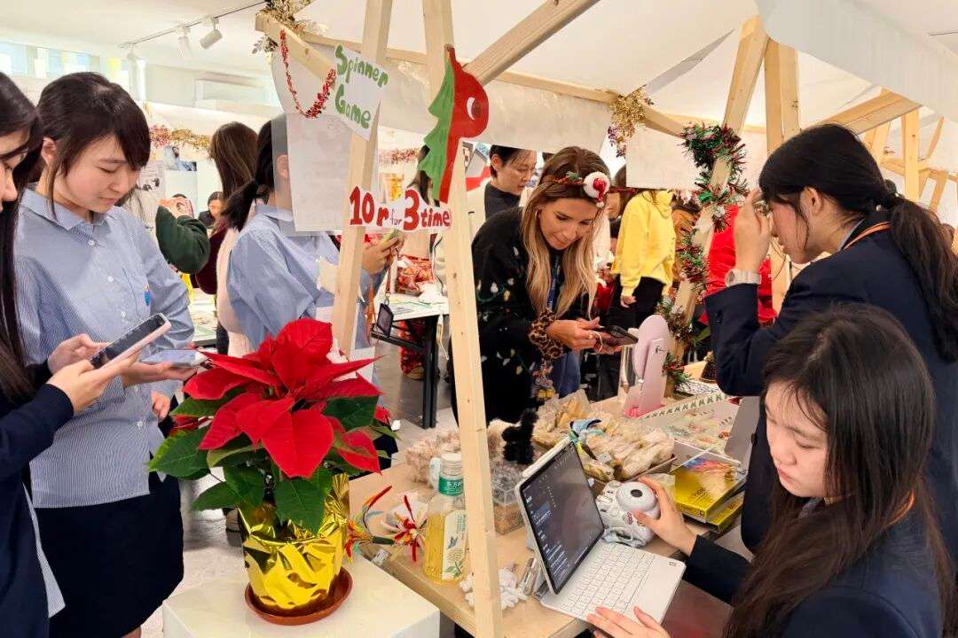 同学在暖冬集市摊位热情服务，介绍手作礼品